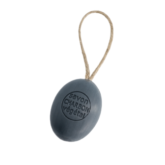 Le Savon corde charbon végétal est un pain de savon ovale gris foncé estampillé de son nom, attaché à une corde en boucle, présenté sur un fond blanc.