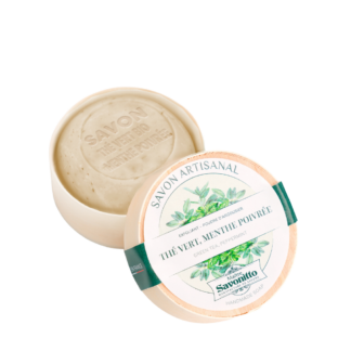 Un savon rond de 100 g, fabriqué à la main et étiqueté "Savon rond le vert menthe poivrée - exfoliant" dans une boîte ronde en carton ouverte. Le savon beige clair est estampillé "SAVON ROND VERT MENTHE POIVRÉE.