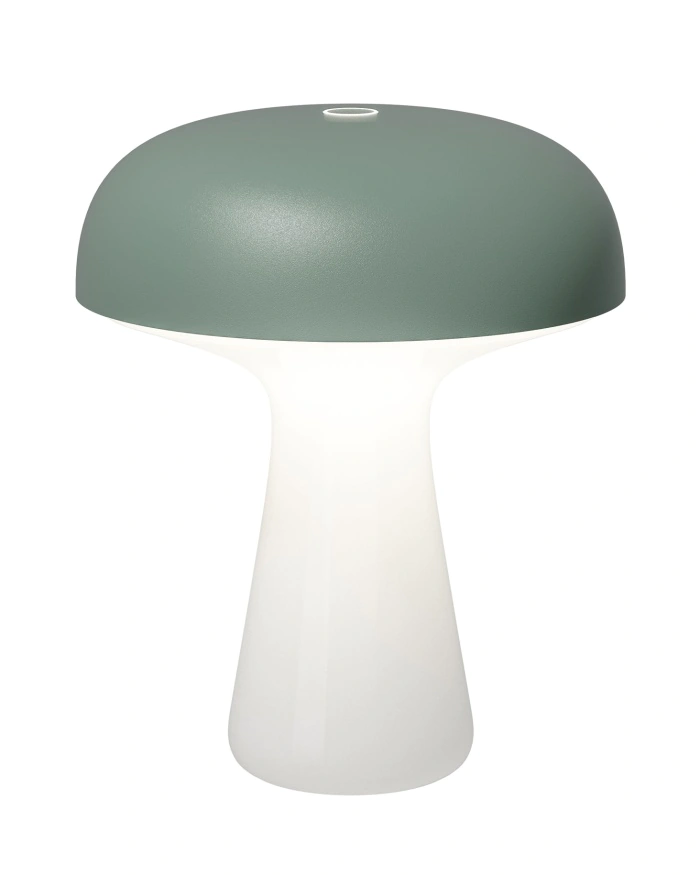 Lampe de table moderne en forme de champignon, avec un sommet en forme de dôme vert mat et une base lisse, blanche et translucide, qui brille doucement sur un fond blanc uni.