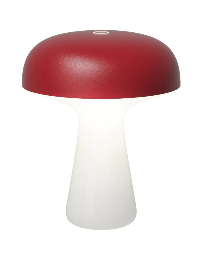 Lampe de table moderne en forme de champignon, avec un sommet en forme de dôme rouge mat et une base cylindrique blanche et lisse. La lampe est allumée et émet une douce lueur sous l'abat-jour rouge.
