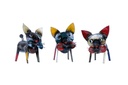 Trois sculptures fantaisistes de Chat upcycling en métal, chacune avec des caractéristiques exagérées uniques et des couleurs aléatoires, sont présentées côte à côte sur un fond blanc.