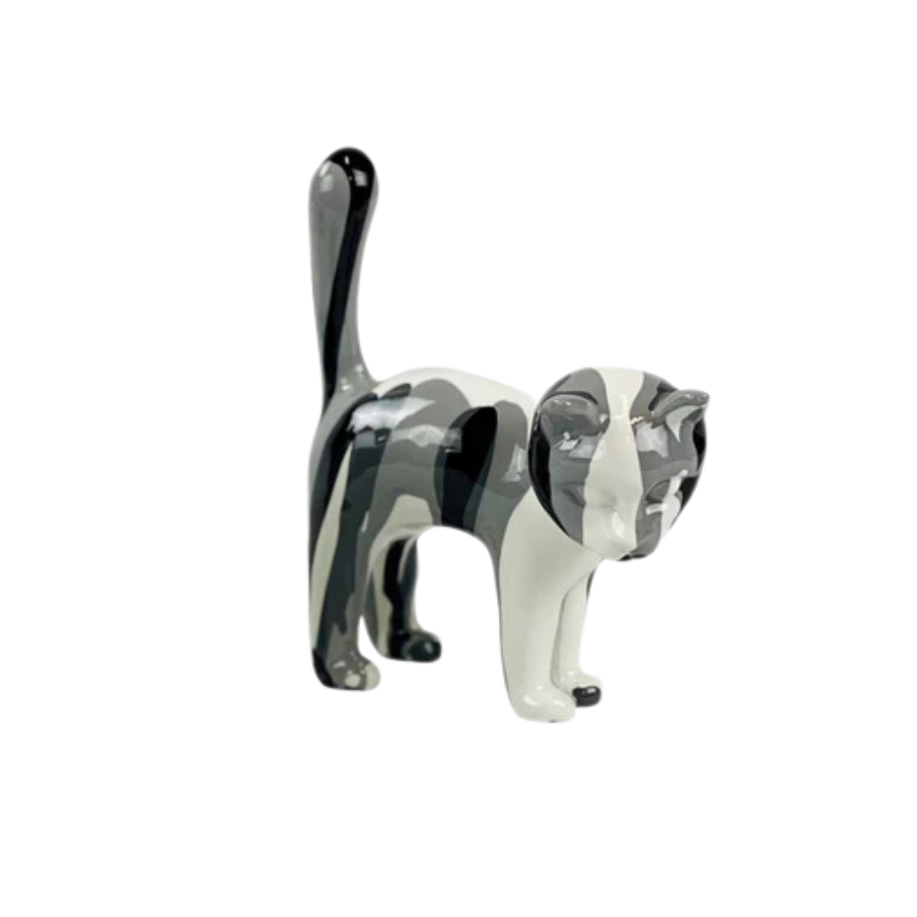 Petite figurine de chat en céramique à la finition brillante, représentant un motif abstrait de camouflage noir, blanc et gris. Le chat se tient debout, la queue relevée. Le fond est blanc.