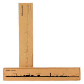 Deux boîtes rectangulaires brunes sont présentées, l'une à la verticale, l'autre à plat, toutes deux avec une illustration Skyline Andernos métal noire et un texte en allemand comprenant "Andenkenstein" et "thul inn".