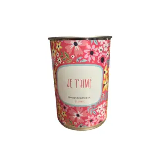 Une boîte de conserve cylindrique, ornée d'un motif floral coloré et d'une étiquette "JE T'AIME" en texte rouge, contient le Kit à semer Je T'aime, qui se détache sur le fond blanc.