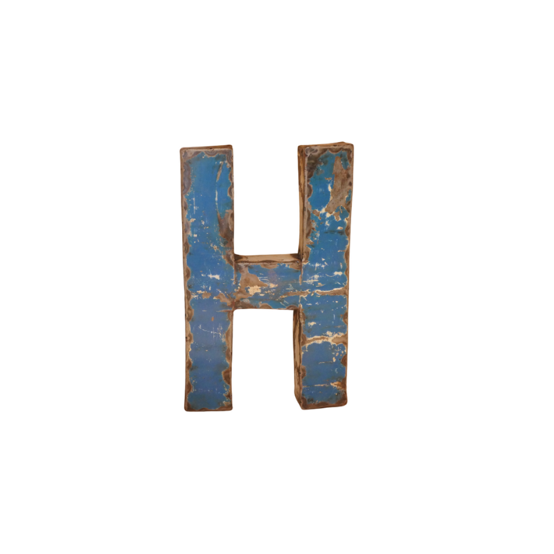 Une grande lettre majuscule "H" à la peinture bleue écaillée et aux bords abîmés par les intempéries laisse apparaître une base brune, faisant écho au style rustique de la Lettre G déco métal recyclé 22cm (Copie), présentée sur un fond blanc.