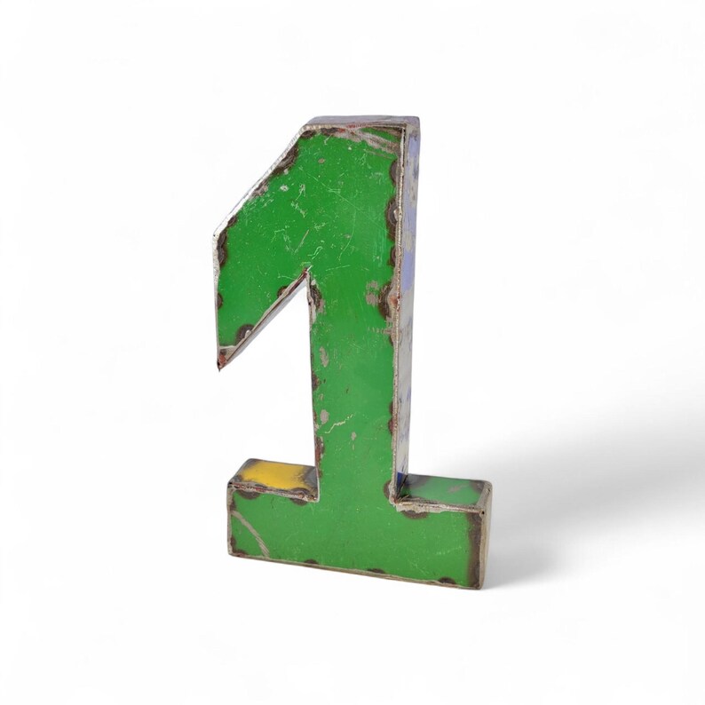 Le Chiffre 1 déco métal recyclé 22 cm est une statue du numéro un en métal vert avec une finition vieillie, qui se tient debout sur un fond blanc. Il est idéal pour compléter votre collection Chiffre 0 déco métal.