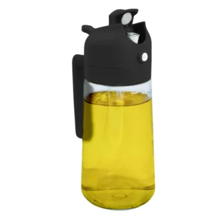 Le Spray Huile Cuisine est un distributeur d'huile en verre transparent avec un couvercle, un bec et une poignée en plastique noir, rempli d'huile de cuisson jaune et présenté sur un fond blanc.