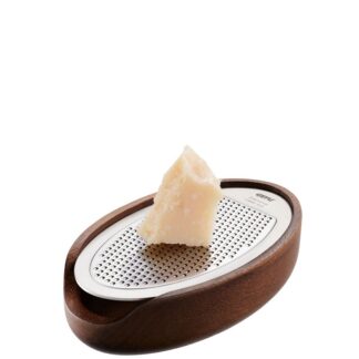 La Râpe Parmezo Bois Inox se compose d'une râpe en acier inoxydable et d'une base en bois, parfaite pour attraper le fromage râpé sous un morceau de fromage placé au-dessus.