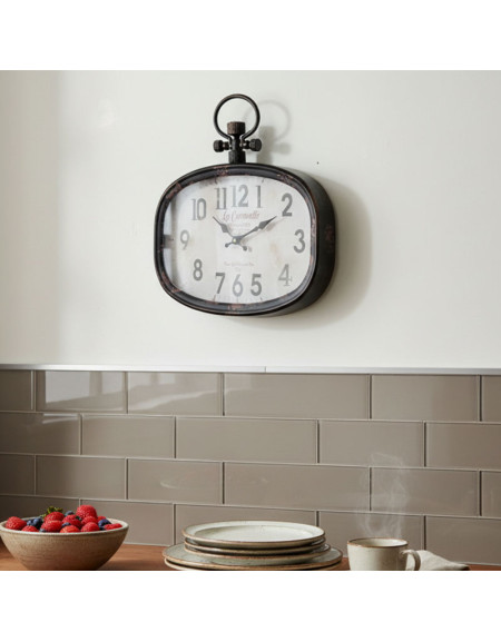 L'Horloge Caravelle Murale, une horloge murale de style ancien, est suspendue au-dessus du dosseret carrelé de la cuisine. En dessous, sur le comptoir, se trouvent un bol de fraises, des assiettes empilées, ainsi qu'une tasse et une soucoupe fumantes.