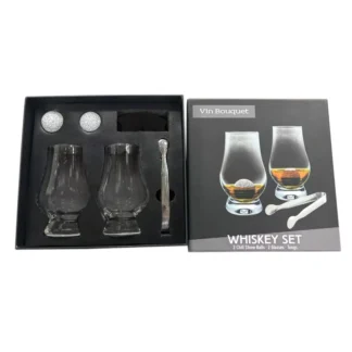 Le Set whisky classique avec pierres granite et pince comprend deux verres, deux pierres à refroidir en granite et une pince dans une boîte noire à côté de l'emballage qui présente les verres remplis et le contenu du set.