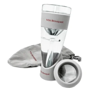 Un "Aérateur de vin avec filtre et sac" transparent et gris est présenté avec une pochette grise à cordon assortie et un filtre rond détachable placé à l'avant.