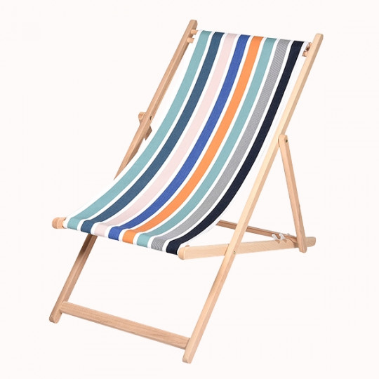La Chaise Longue Hêtre est une chaise longue en bois dont l'assise en tissu présente des rayures verticales bleues, sarcelles, orange, marines et blanches sur un fond blanc uni.