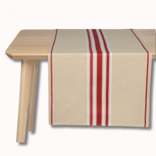Un chemin de table beige avec des rayures verticales rouges et blanches est soigneusement posé sur une table en bois clair sur un fond blanc uni.
