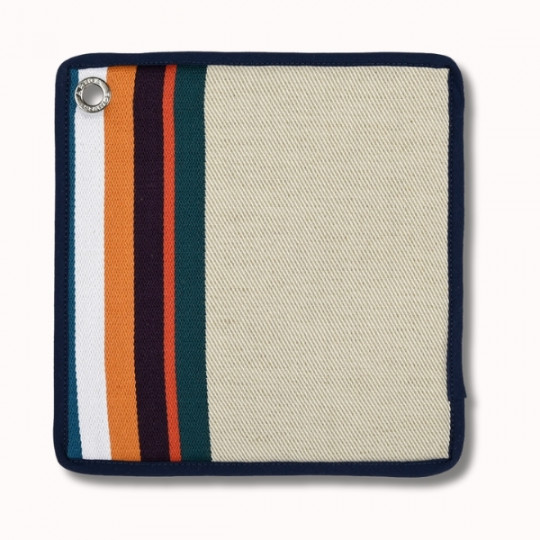 Cache-pot carré en tissu avec une bordure marine, comportant des rayures verticales en blanc, bleu clair, orange et violet foncé sur un côté et un œillet de suspension en métal dans le coin. Le reste du cache-pot est beige.