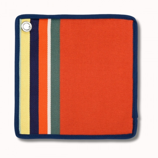 Une manique carrée en tissu avec un centre orange vif, bordé de bleu foncé. Le côté gauche présente des rayures verticales jaunes, bleu marine, orange et vertes, avec un anneau métallique dans le coin supérieur gauche.