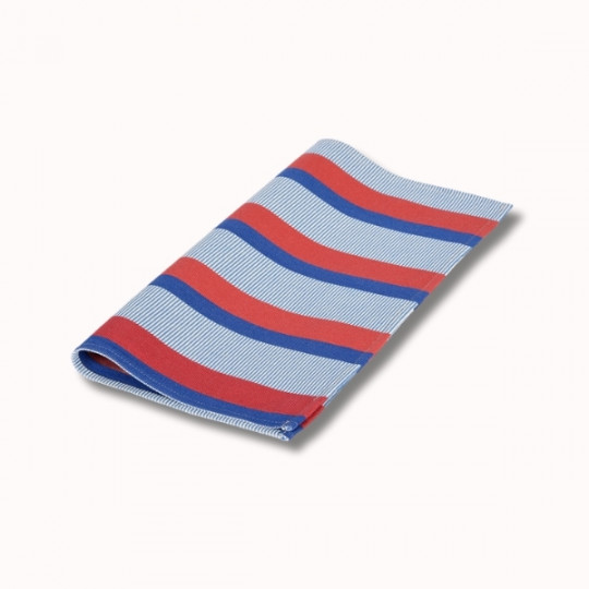 Un tissu soigneusement plié avec des rayures diagonales rouges et bleues alternées sur un fond blanc, photographié sur une surface unie blanc cassé.