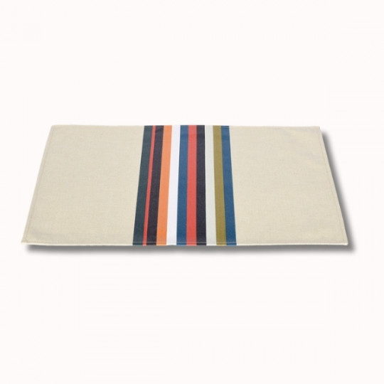 Le Set Table Enduit (6 coloris) est un set de table rectangulaire de couleur beige avec des rayures verticales bleues, orange, rouges, blanches, noires et vertes sur une face, sur un fond clair uni.