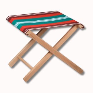 Le Pliant Outdoor est un petit tabouret pliant avec un cadre en bois et une assise en tissu rayé rouge, vert, blanc et marron.