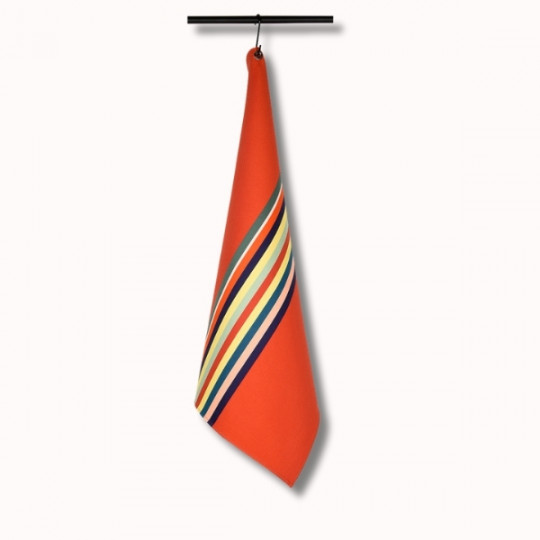 Le Torchon 70x53 (6 coloris), un tissu orange vif avec des bandes diagonales multicolores, est présenté suspendu à une tringle noire sur un fond blanc uni.