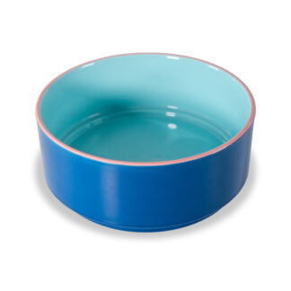 Un bol rond en céramique avec un extérieur bleu brillant, un intérieur bleu clair et un fin bord rose, posé sur une surface blanche.