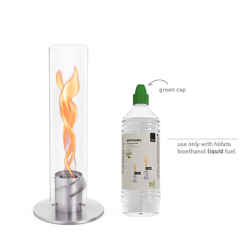 Une cheminée de table höfats SPIN classic 900 argent – Bioéthanol, avec une flamme tourbillonnante, est posée à côté d'une bouteille de combustible liquide au bioéthanol höfats munie d'un bouchon vert. Une mention indique de n'utiliser que du combustible liquide au bioéthanol höfats.