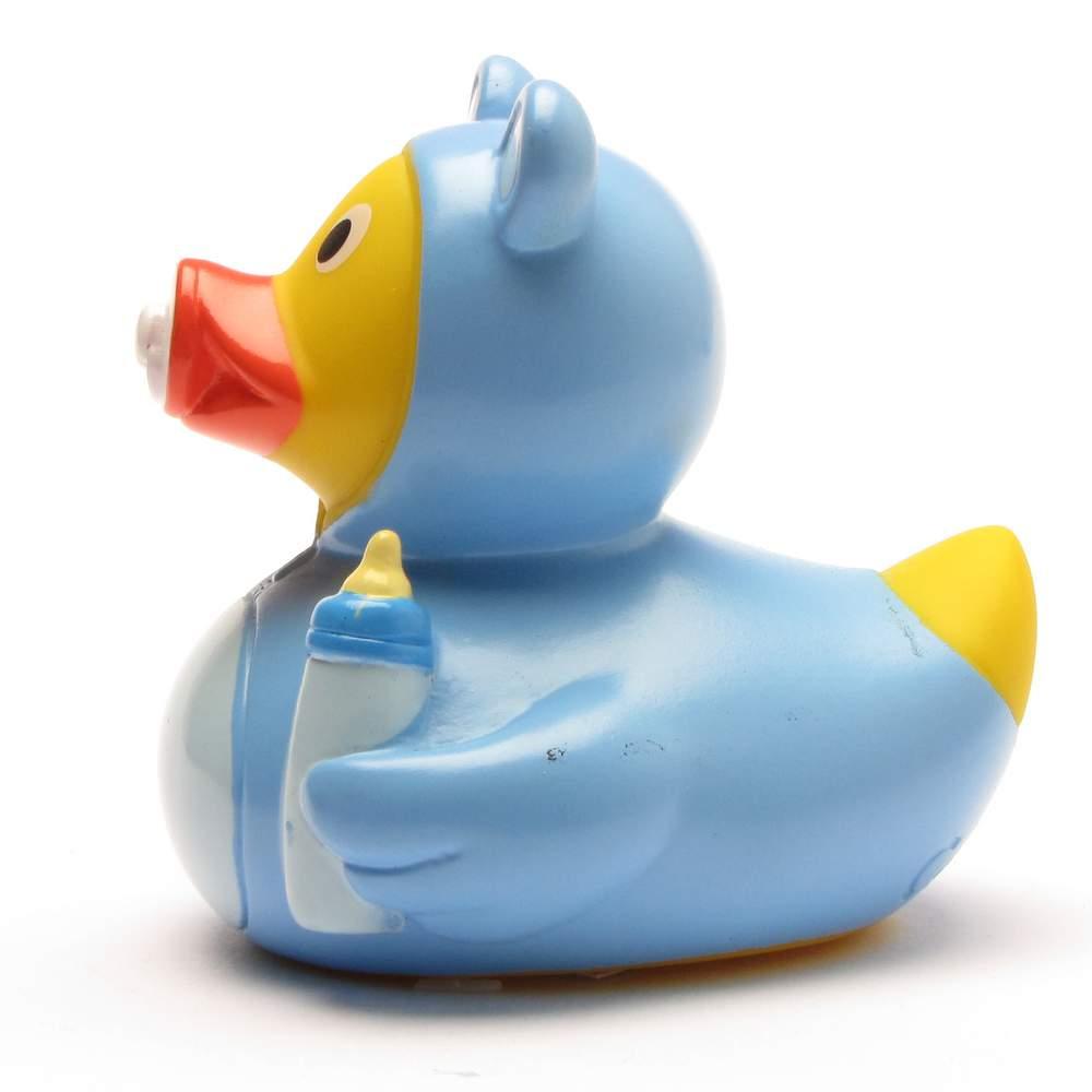 On voit de profil un canard de bain « Baby Garçon » vêtu d'une tenue bleue pour bébé avec une capuche, tenant un biberon et avec une tétine rouge dans le bec.