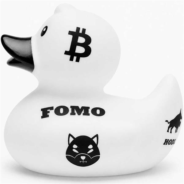 Canard de bain « Baby Garçon » représentant un canard en caoutchouc blanc arborant un symbole Bitcoin noir sur la tête, le mot « FOMO » sur le flanc, un visage d’animal stylisé en dessous, ainsi qu’une silhouette partielle de taureau accompagnée de l’inscription « HODL » près de la queue.