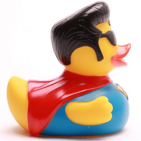 Un canard en caoutchouc déguisé en super-héros, avec des cheveux noirs, des lunettes de soleil, une cape rouge et un costume bleu, vu de profil.