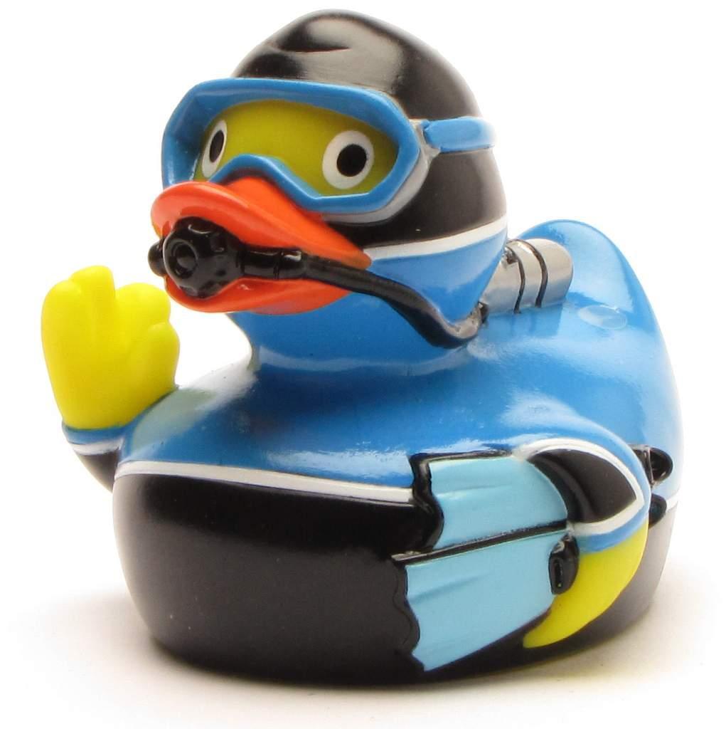 Un canard en caoutchouc déguisé en plongeur, vêtu d'un équipement bleu et noir, portant des lunettes de plongée et un tuba, et levant une aile comme pour faire un signe de la main.