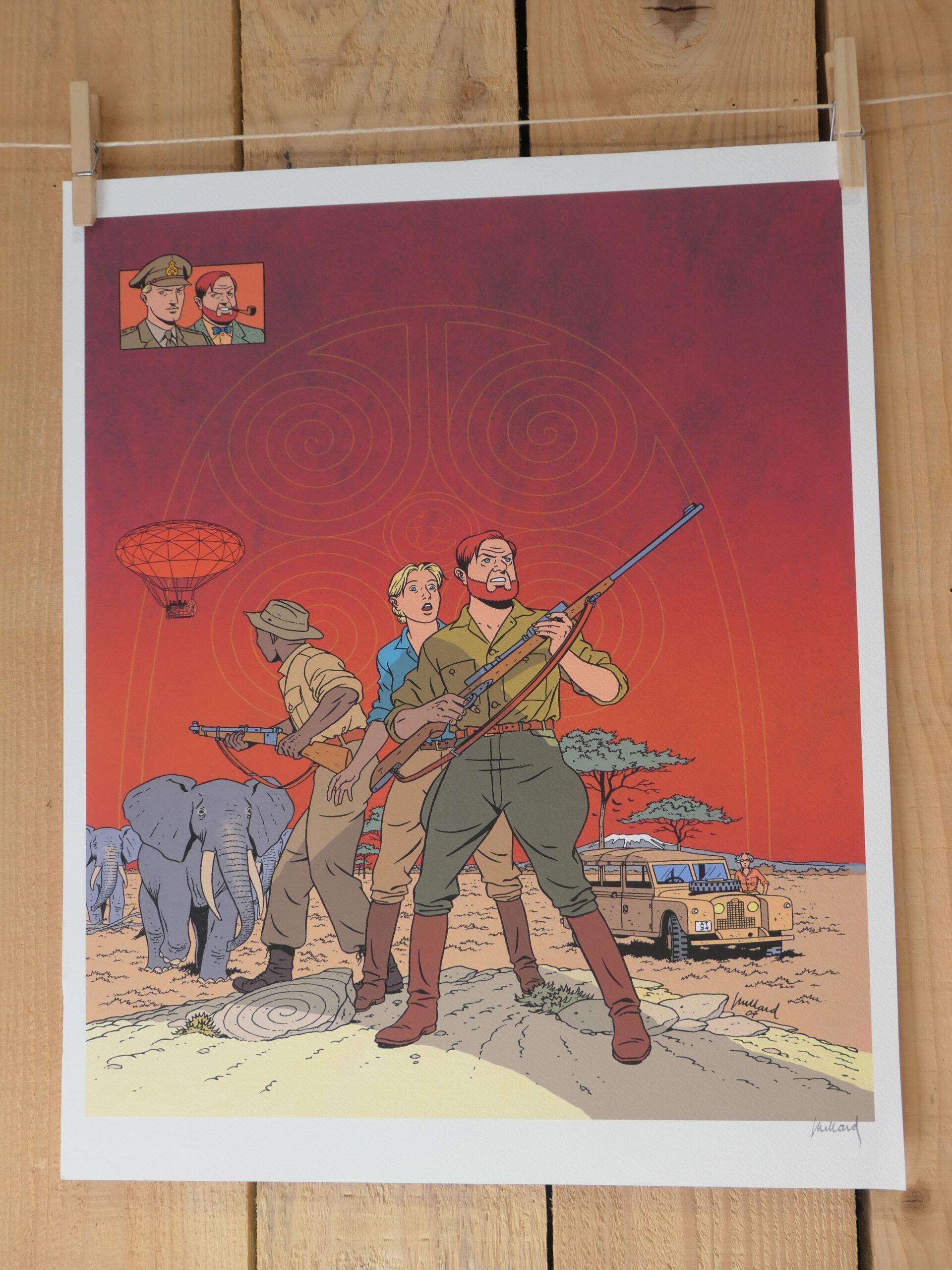 Trois personnes en tenue de safari, accompagnées d’éléphants et d’une jeep sous un ciel rouge, se tiennent dans un paysage africain sur la « Lithographie André Juillard – Blake et Mortimer : Savane – 40 × 50 cm ». Un petit encart en haut de l’image montre deux visages, avec des arbres et un parachute visibles à l’arrière-plan.