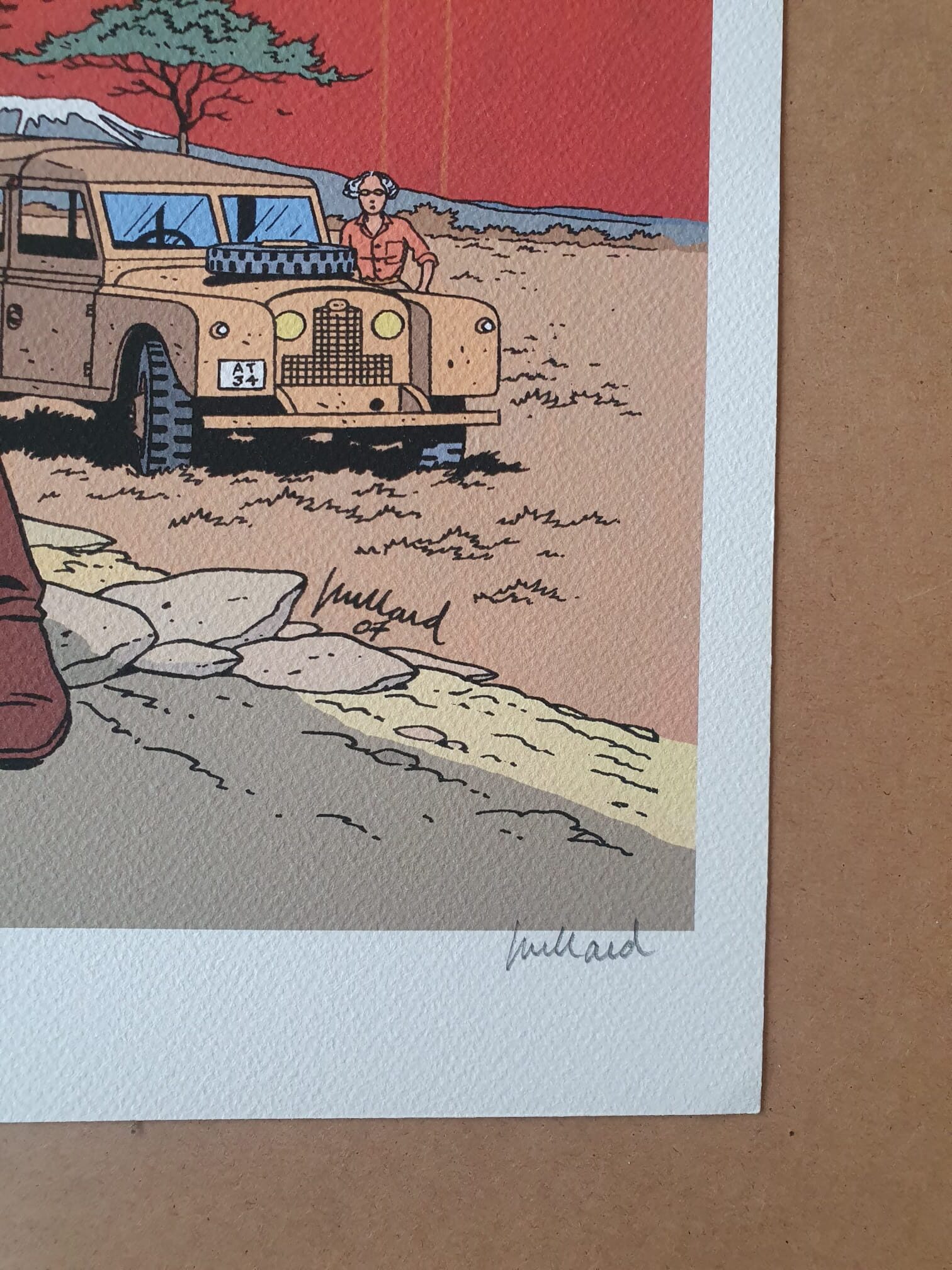 Un gros plan de l'illustration de bande dessinée « Lithographie André Juillard – Blake et Mortimer : Savane – 40 × 50 cm » montre une Land Rover d'époque, une personne debout à côté, un arbre et un paysage. L'illustration est signée « André Juillard » à deux endroits : une fois sur l'illustration elle-même et une fois sur la bordure blanche.