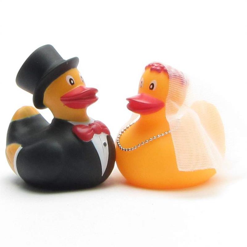 Deux canards en caoutchouc déguisés en mariés ; le canard marié porte un smoking et un haut-de-forme, tandis que la canarde mariée porte un voile et un collier.