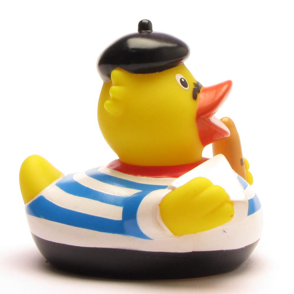 On voit, sur un fond blanc, un canard en caoutchouc jaune coiffé d'un béret noir et vêtu d'une chemise rayée bleue et blanche, tenant une baguette sous son aile.