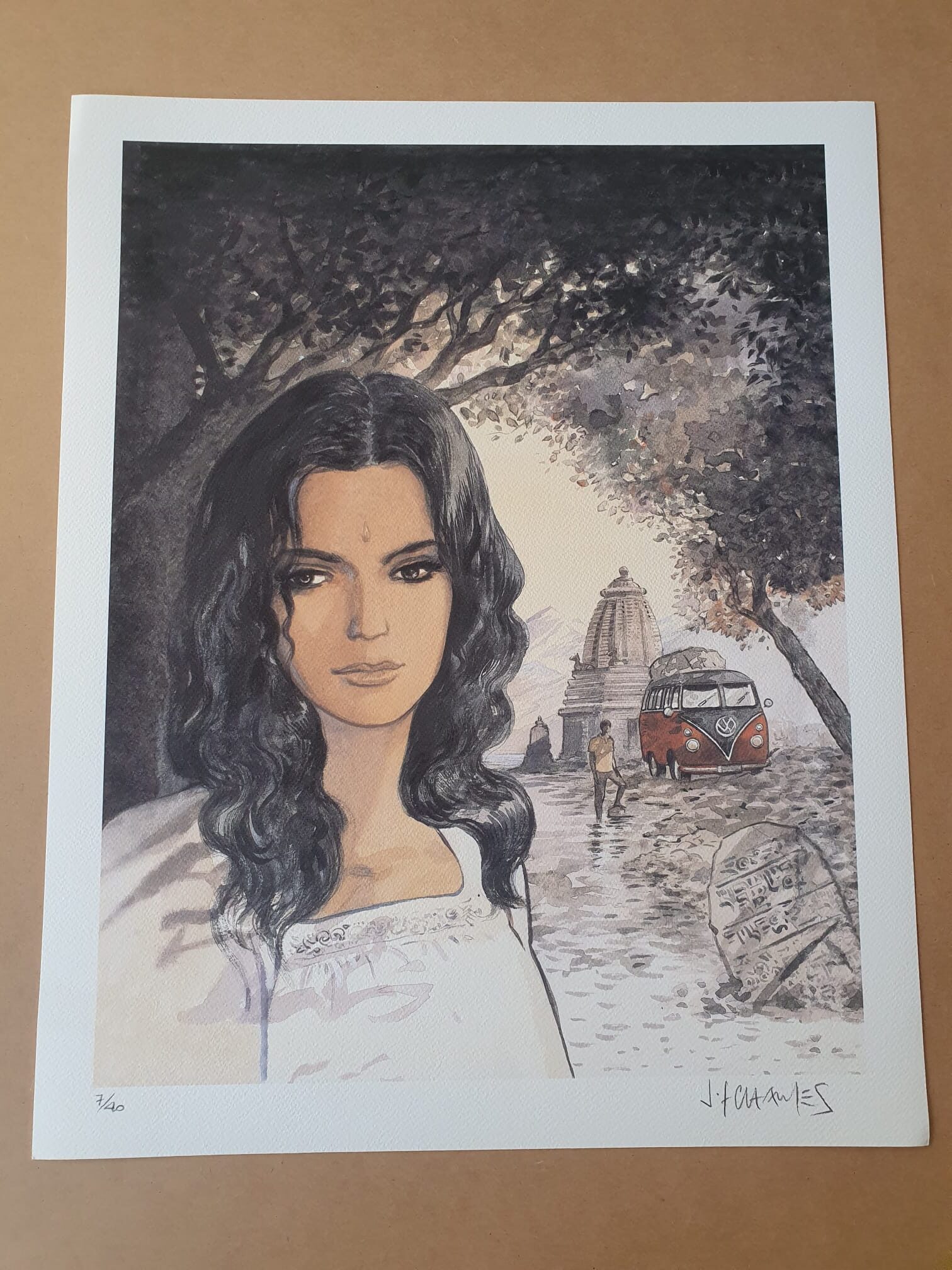 La « Lithographie Jean-François Charles – Femme et VW – 40 × 50 cm » représente une femme aux longs cheveux bruns debout devant un temple, avec en arrière-plan un combi VW rouge et un sentier où une silhouette se promène à l’ombre des arbres, le tout créant une ambiance rétro et sereine.
