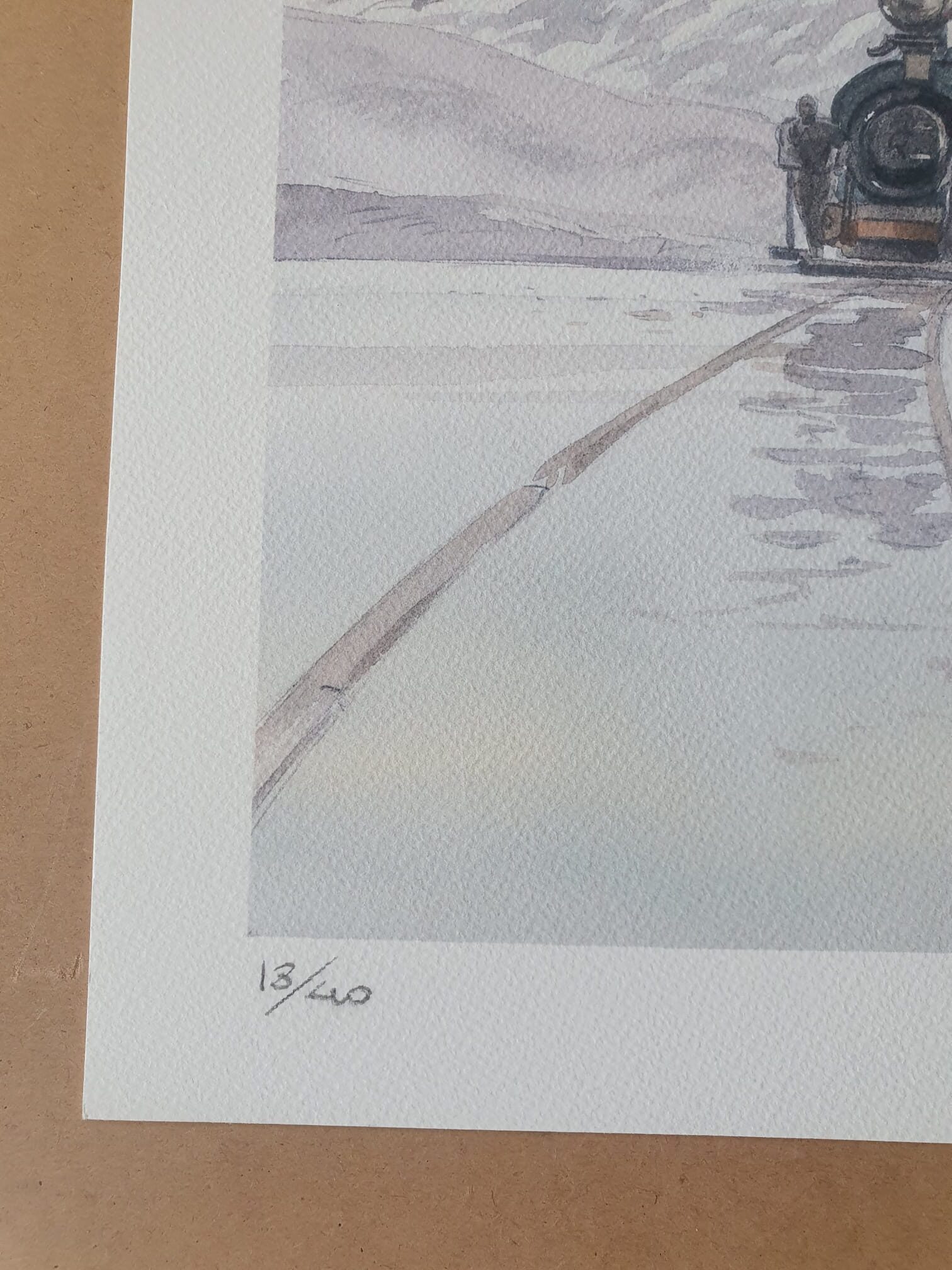Gros plan sur la « Lithographie Jean-François Charles – L’Homme au parapluie – 40 × 50 cm », représentant des traces dans la neige et une partie d’une locomotive à vapeur. L’estampe est numérotée à la main au crayon « 13/40 » dans le coin inférieur gauche.
