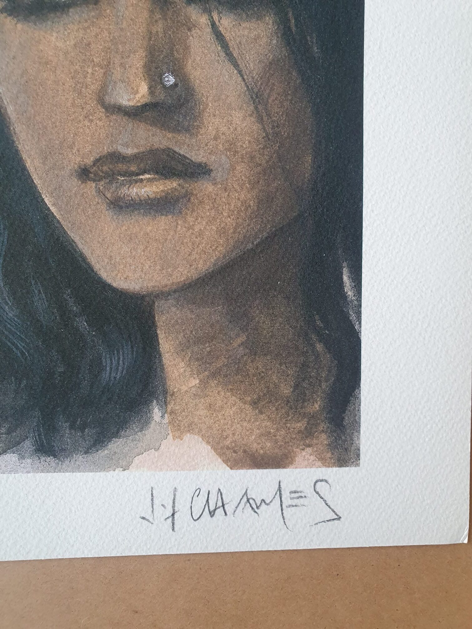 Un gros plan de l’œuvre « Lithographie Jean-François Charles – Visages – 40 × 50 cm » montre la moitié inférieure du visage d’une femme aux longs cheveux foncés ; la signature de l’artiste figure sous l’œuvre, réalisée sur du papier texturé.