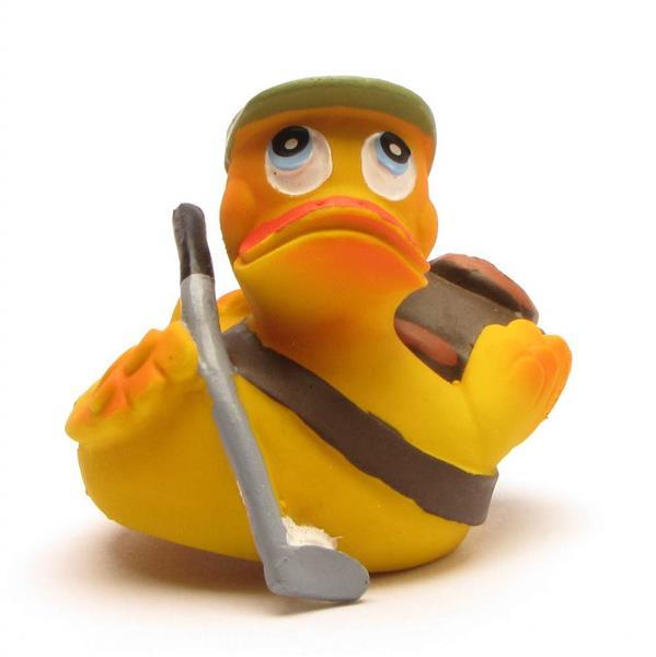 Un canard en caoutchouc jaune déguisé en golfeur, coiffé d'une casquette verte, tenant un club de golf gris et portant un sac de golf marron en bandoulière.
