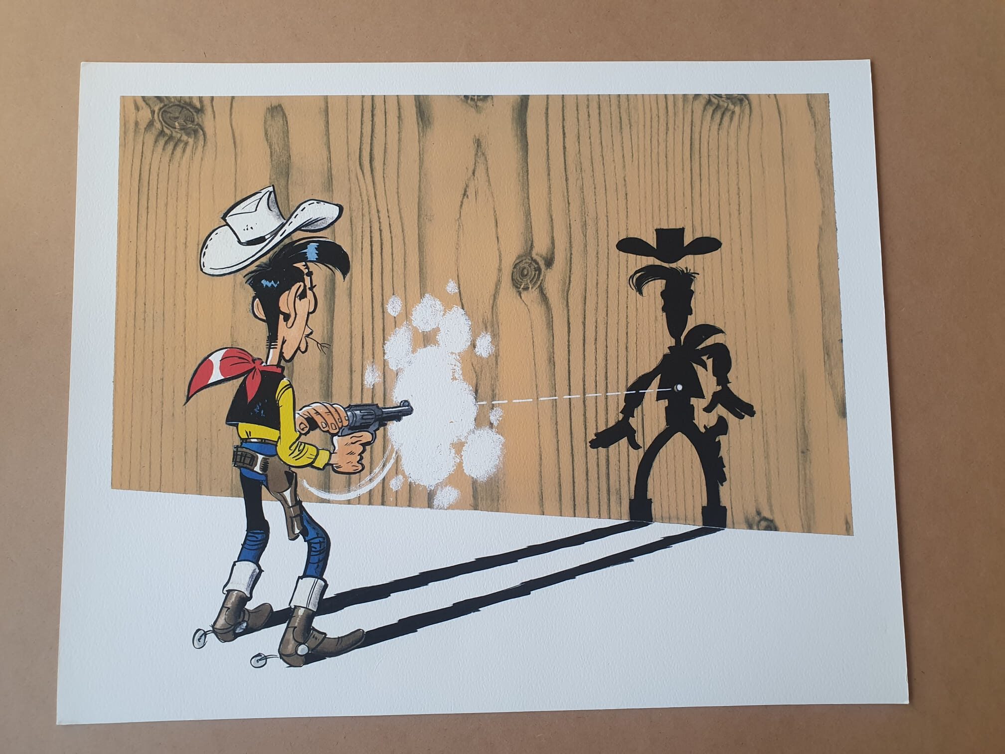 Bien sûr ! Voici une version révisée de votre phrase en utilisant les données produit fournies : Dans la lithographie « Morris – Lucky Luke : L’homme qui tire plus vite que son ombre » (40 × 50 cm), Lucky Luke — un cow-boy de bande dessinée — pulvérise de la peinture blanche sur un mur en bois, recouvrant ainsi l’ombre d’un autre cow-boy tandis que sa propre ombre reste visible à côté de la zone fraîchement peinte.