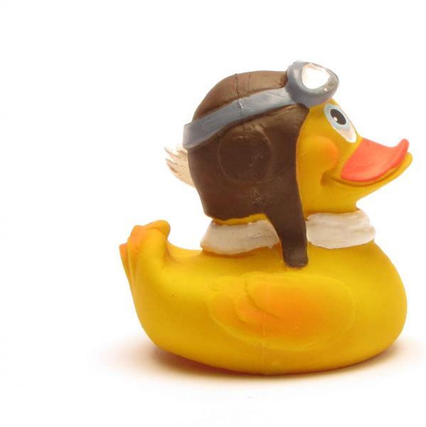 Un canard en caoutchouc jaune portant un casque d'aviateur marron avec des lunettes de protection et une écharpe blanche, tourné vers la droite, sur un fond blanc uni.
