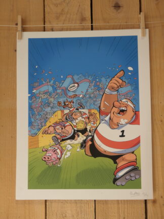 Cette œuvre, intitulée « Lithographie Jean-Charles Poupard – Rugby 1 – 40 × 50 cm », représente un joueur de rugby exultant qui court avec le ballon, suivi de ses coéquipiers, d’un cochon et d’une poule, tandis que des supporters enthousiastes agitent des drapeaux dans les tribunes. L’illustration est mise en valeur sur un fond en bois.