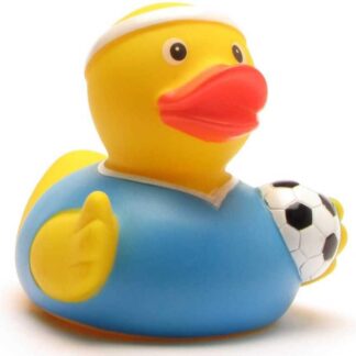 Un canard en caoutchouc jaune, portant un bandeau blanc et un t-shirt bleu, qui tient un petit ballon de foot noir et blanc sous son aile.