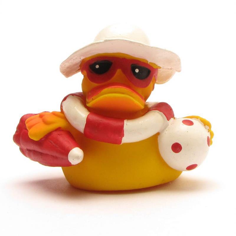Un canard en caoutchouc jaune porte des lunettes de soleil, un chapeau blanc et une écharpe rouge et blanche ; il tient un ballon de plage rouge et blanc et semble prêt pour l'été.