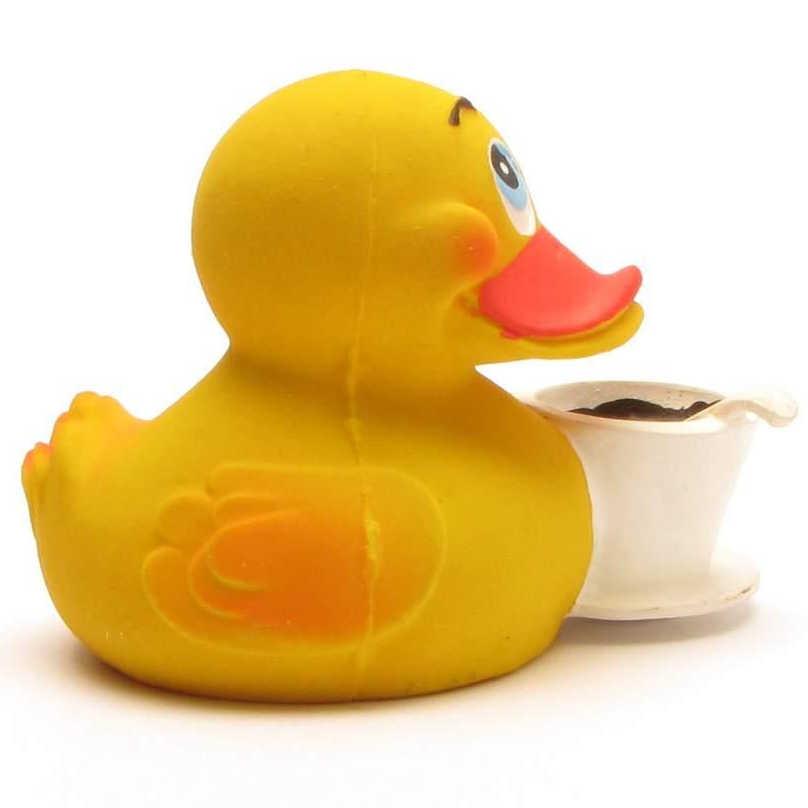 Un canard en caoutchouc jaune au bec orange est posé à côté d'une petite tasse à thé blanche.