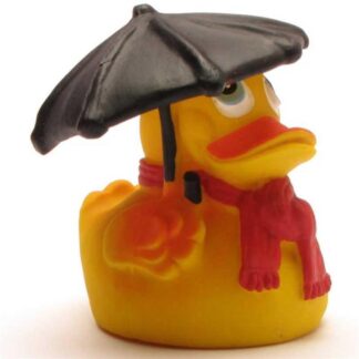 Un canard en caoutchouc jaune qui porte une écharpe rouge et tient un parapluie noir au-dessus de sa tête.