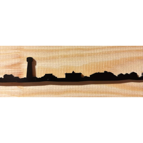 Panneau mural « Skyline » d'Andernos-les-Bains en métal noir – 30 cm représentant la silhouette noire de la ville, avec notamment une grande tour et divers bâtiments, sur un fond en bois clair.