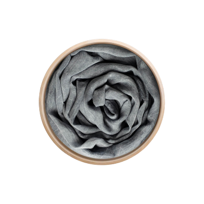 Un foulard en bambou Innbamboo Tinta Unita, présenté enroulé dans un récipient circulaire en bois, vu de dessus sur fond blanc.
