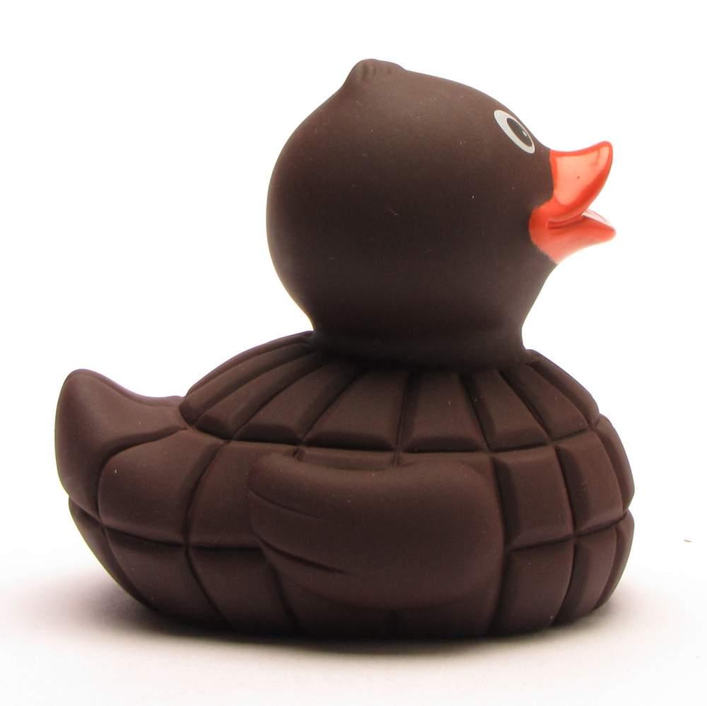 Un canard en caoutchouc qui semble être en chocolat, avec un bec orange et des yeux blancs, représenté de profil sur un fond blanc.