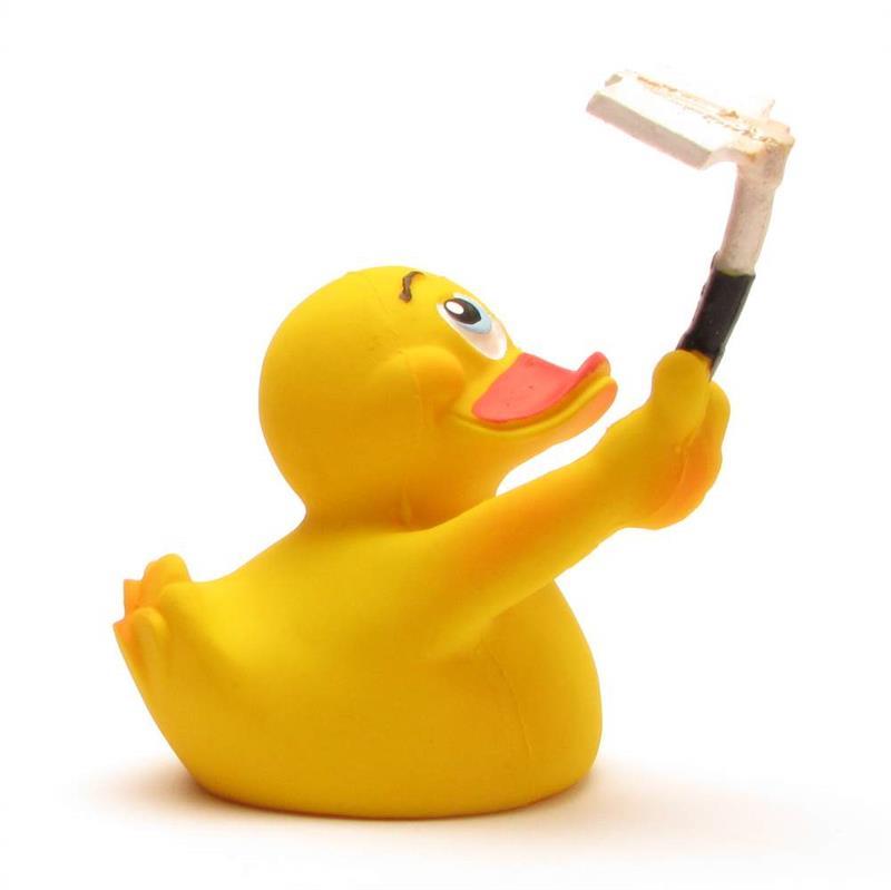 Un canard en caoutchouc jaune tient dans son aile une perche à selfie blanche et noire, prenant la pose comme s'il prenait un selfie sur fond blanc.