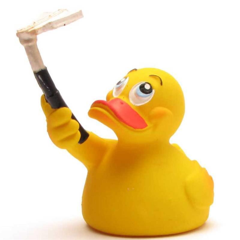 Un canard en caoutchouc jaune tient une perche à selfie noire à laquelle est fixé un téléphone ; il lève les yeux, les yeux écarquillés et le bec ouvert.