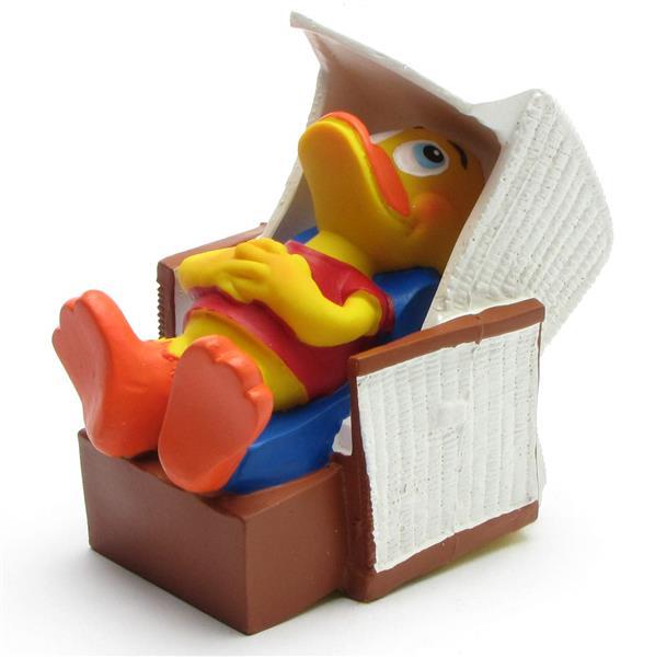 Un canard de dessin animé jaune est allongé sur une chaise longue bleue dotée d'un auvent blanc et d'un piètement marron ; il porte une chemise rouge et a l'air détendu.